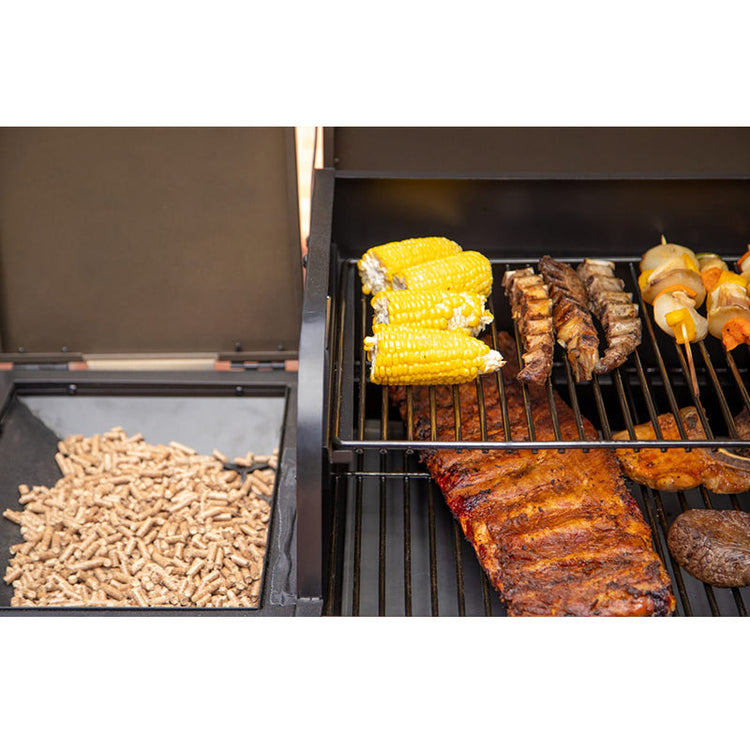 Grill with various meats and vegetables cooking on a white background