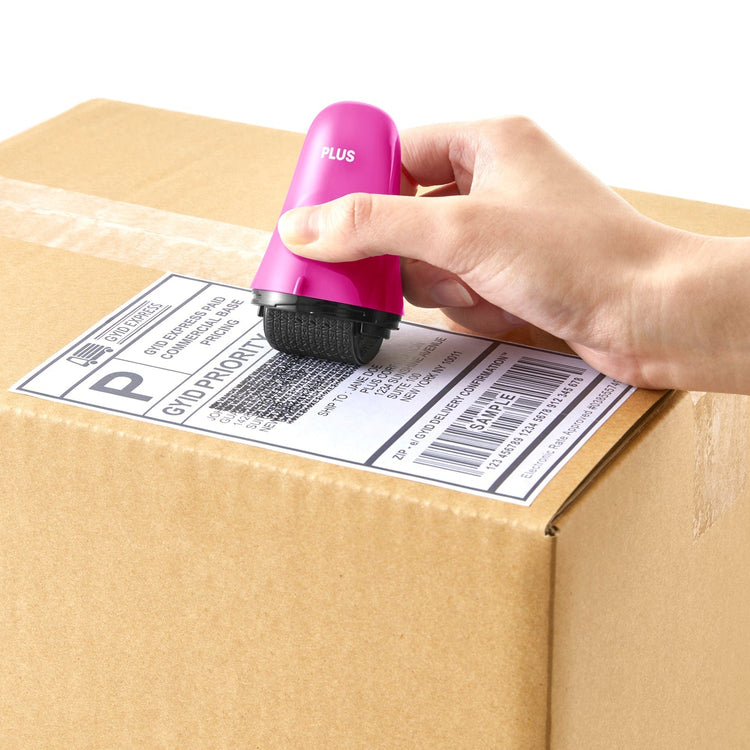 Hand using a pink label printer to apply a barcode label on a cardboard box.