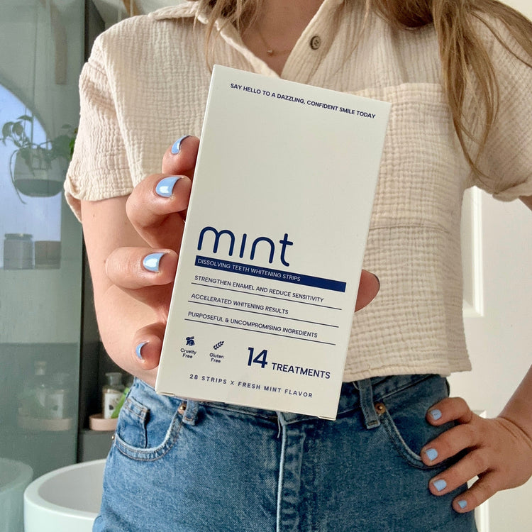 Person holding a box of Mint dental strips with a neutral background