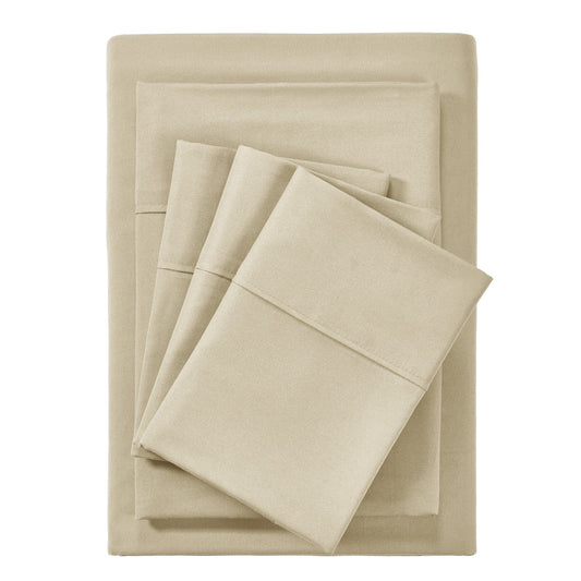A warm taupe colored 6-piece bamboo sheet set on a bed, with a flat sheet, fitted sheet, and pillowcases displayed. The bed is set against a room backdrop with a plant and nightstand on the side.