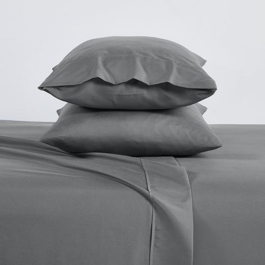 A charcoal grey 6 piece bamboo sheet set displayed on a bed, including a fitted sheet, a flat sheet, and pillow covers with a second pillow placed on the bed.