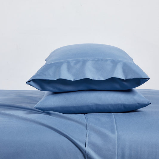 A set of ocean blue bamboo sheets displayed on a bed, including a fitted sheet, a flat sheet, and pillowcases.