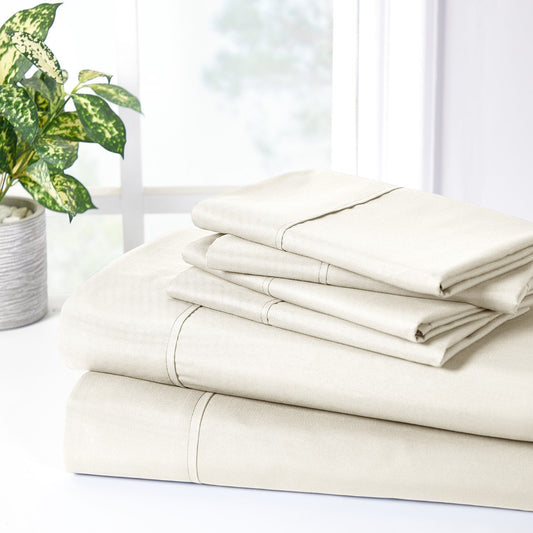 A cream-colored bamboo sheet set on a bed, including a fitted sheet, flat sheet, and pillowcases, with a wooden headboard and houseplants in the room.
