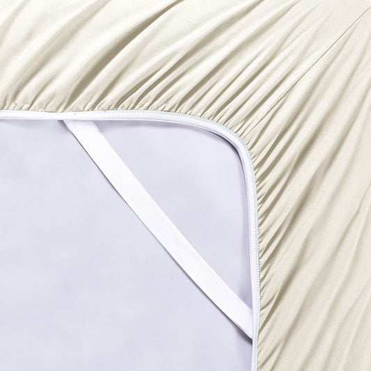 A cream-colored bamboo sheet set on a bed, including a fitted sheet, flat sheet, and pillowcases, with a wooden headboard and houseplants in the room.