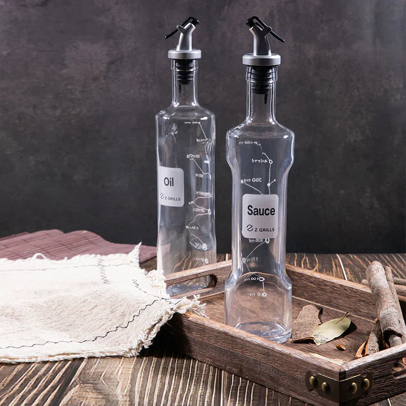Two clear glass bottles labeled 'Oil' and 'Sauce' on a wooden tray with a dark background.