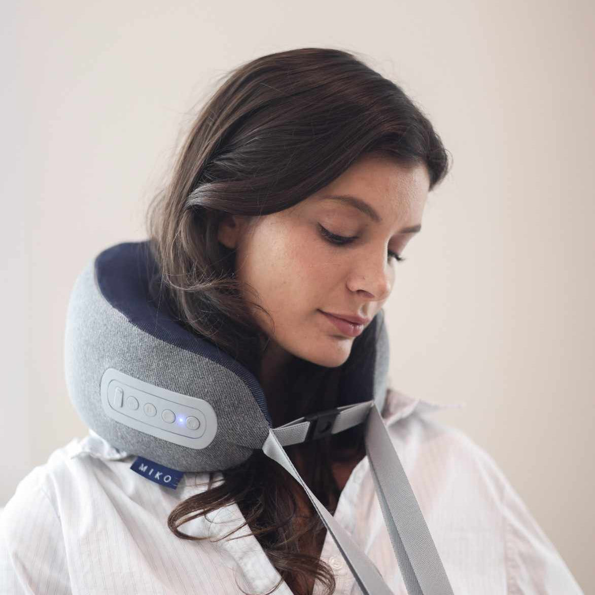Woman using a neck pillow with a neutral background