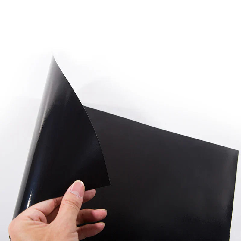 Hand holding a sheet of black vinyl against a white background