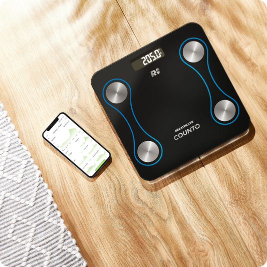 A black digital smart scale with blue decorative elements and silver brand logos, displaying a weight reading.