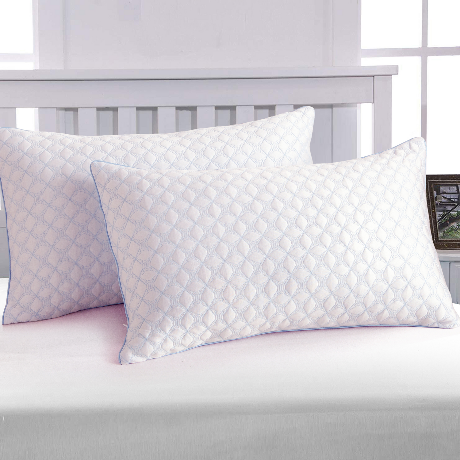 Two white pillows with a subtle pattern on a bed in a bedroom setting.