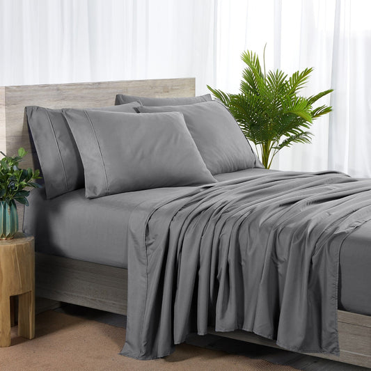A charcoal grey 6 piece bamboo sheet set displayed on a bed, including a fitted sheet, a flat sheet, and pillow covers with a second pillow placed on the bed.