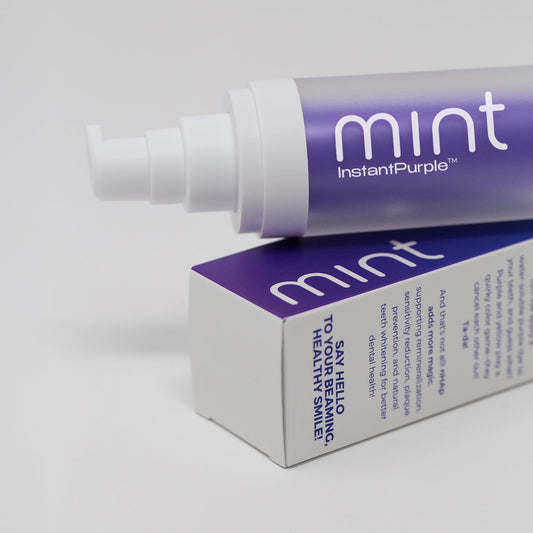 A product image showing a box and tube of Mint InstantPurple Color Corrector with nHAp. The packaging is primarily purple and white with text detailing the product's benefits and instructions for use.