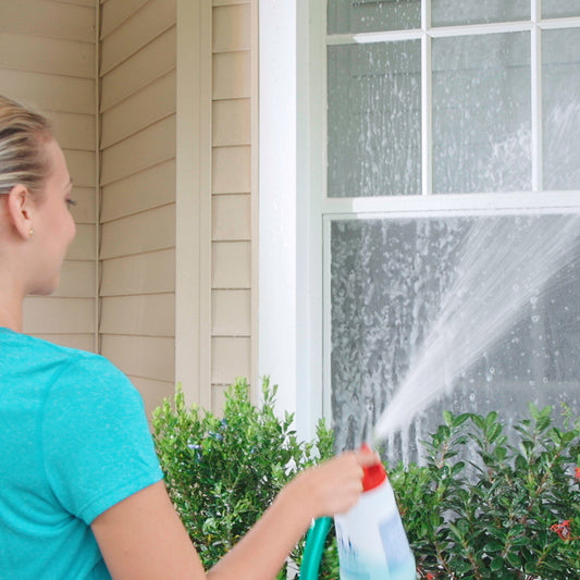 Person using a hose to clean the exterior of a house