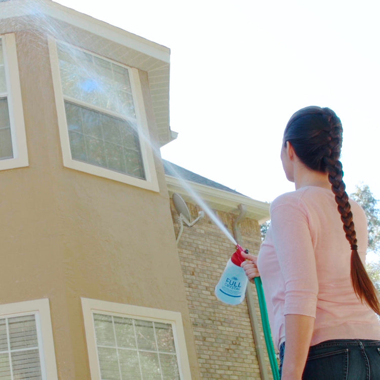 Person using a pressure washer to clean the exterior of a house
