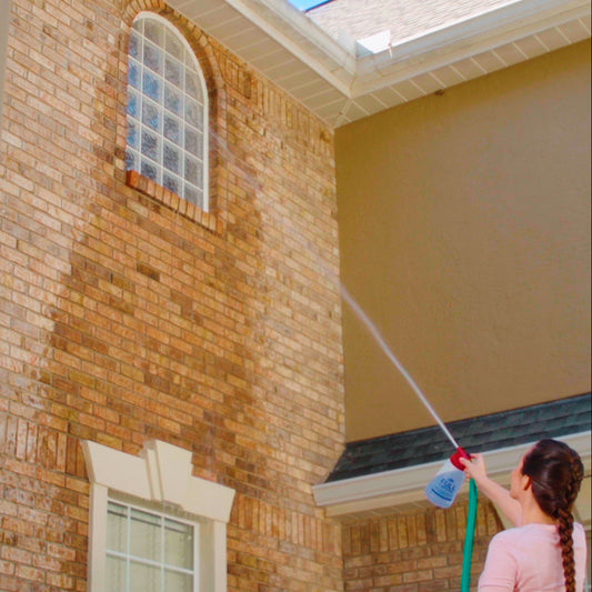 Person using a hose to clean the exterior of a house