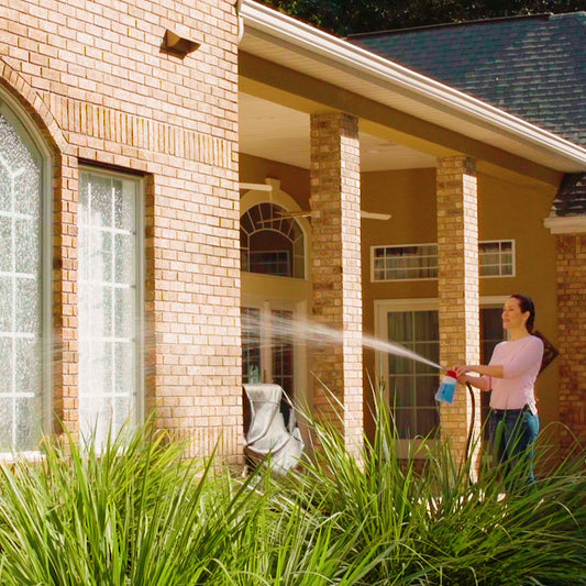 Person using a hose to clean the exterior of a house