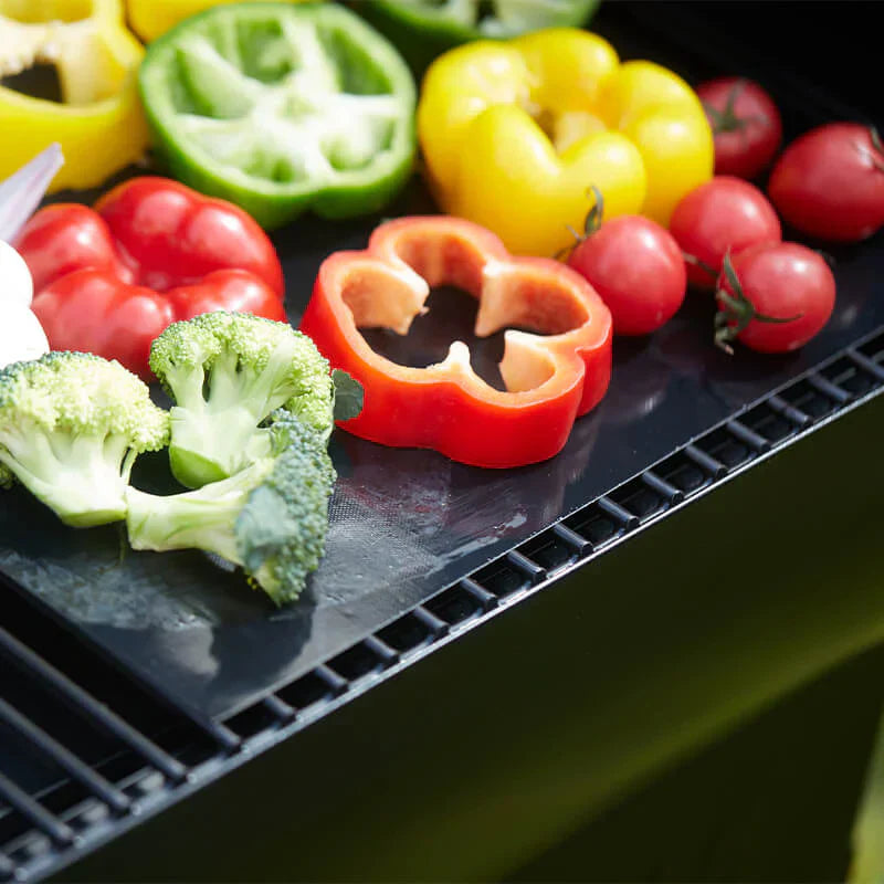 Assorted vegetables including bell peppers, broccoli, and tomatoes on a grill.