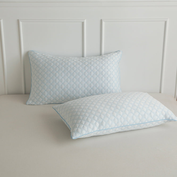 Two quilted pillows on a bed with a neutral headboard.